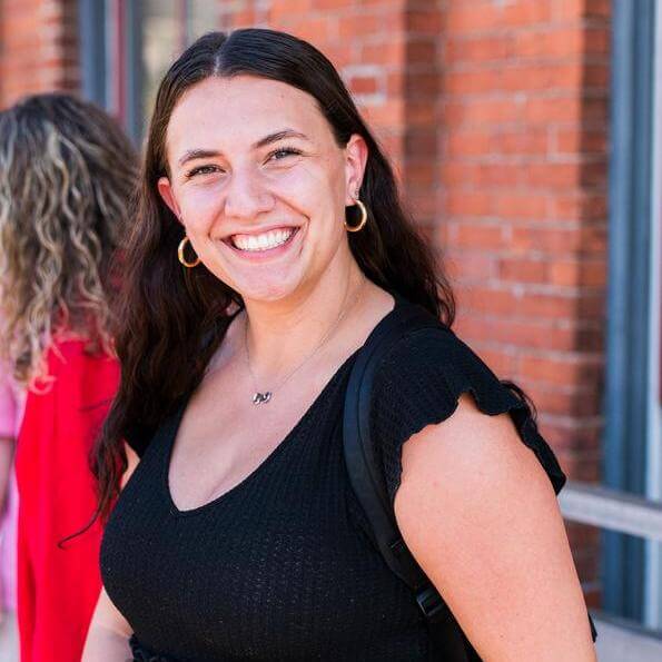 Madison Gioffreda smiles wearing a black shirt in front of a brick background.